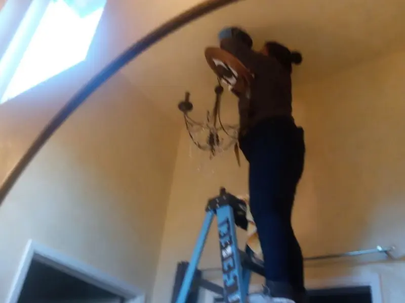 Electrician installing a chandelier in a Luzerne residence